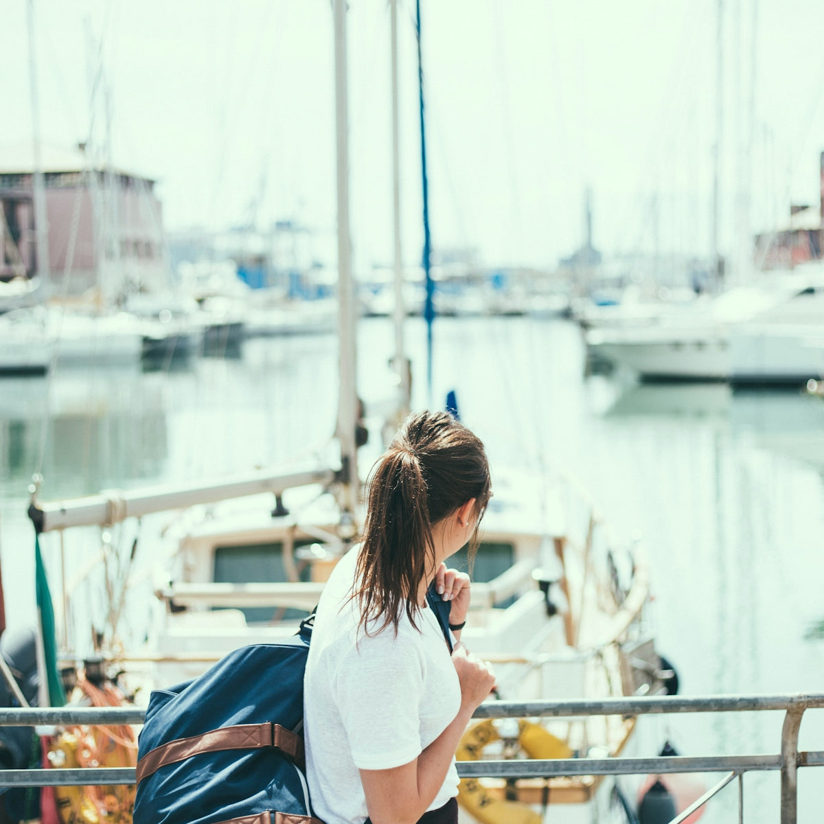 woman wearing white shirt holding blue duffel bag
