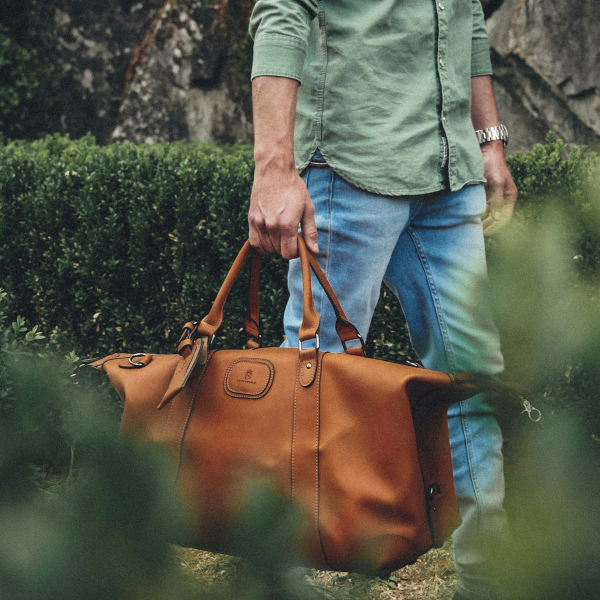 man holding bag near grass