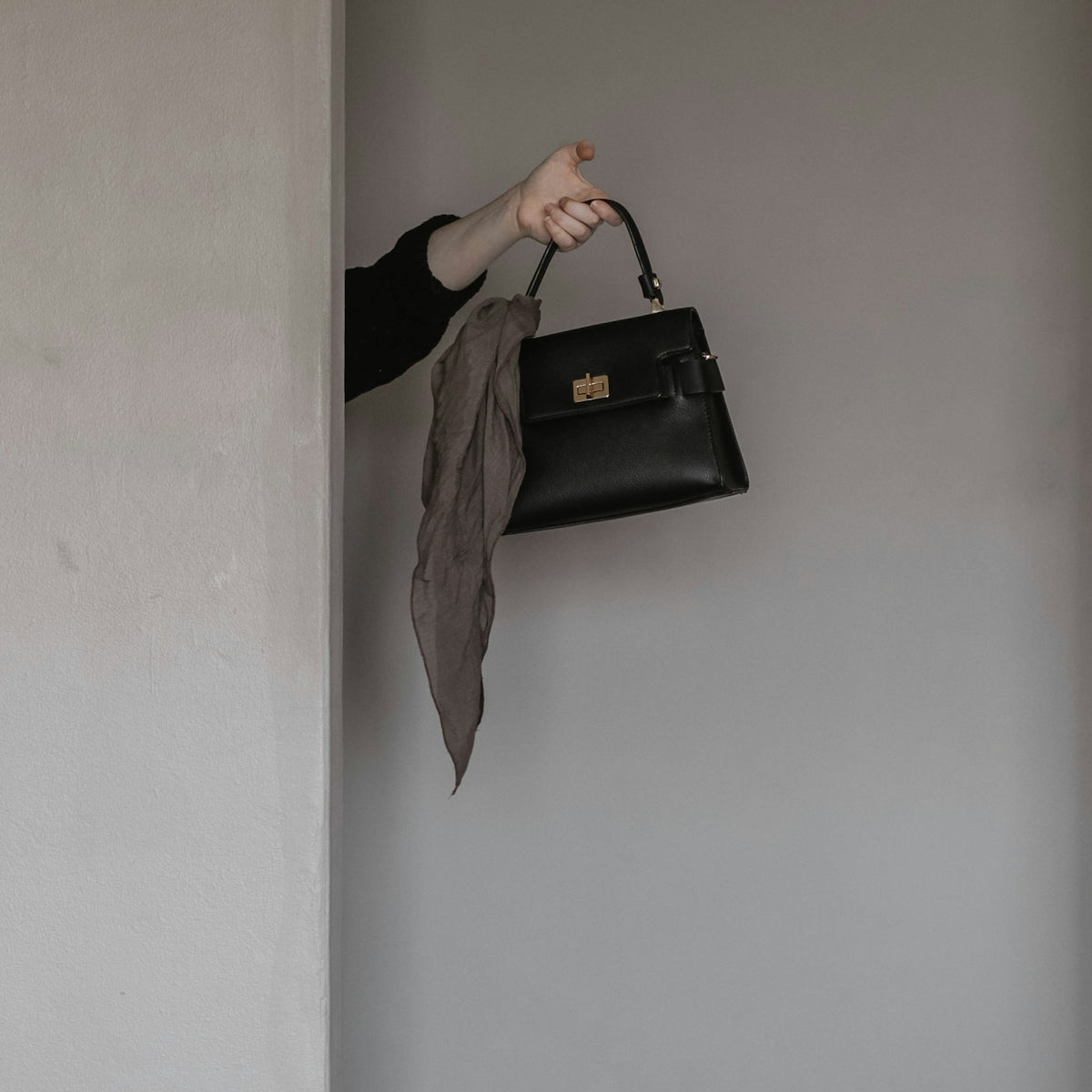 person holding black leather handbag