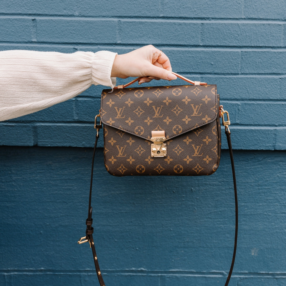 person holding brown leather sling bag