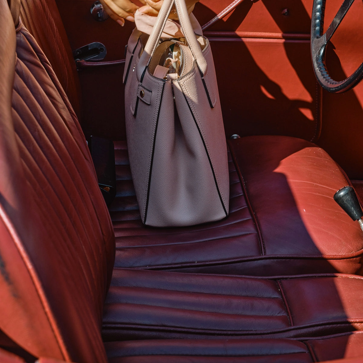gray leather handbag on brown leather car seat