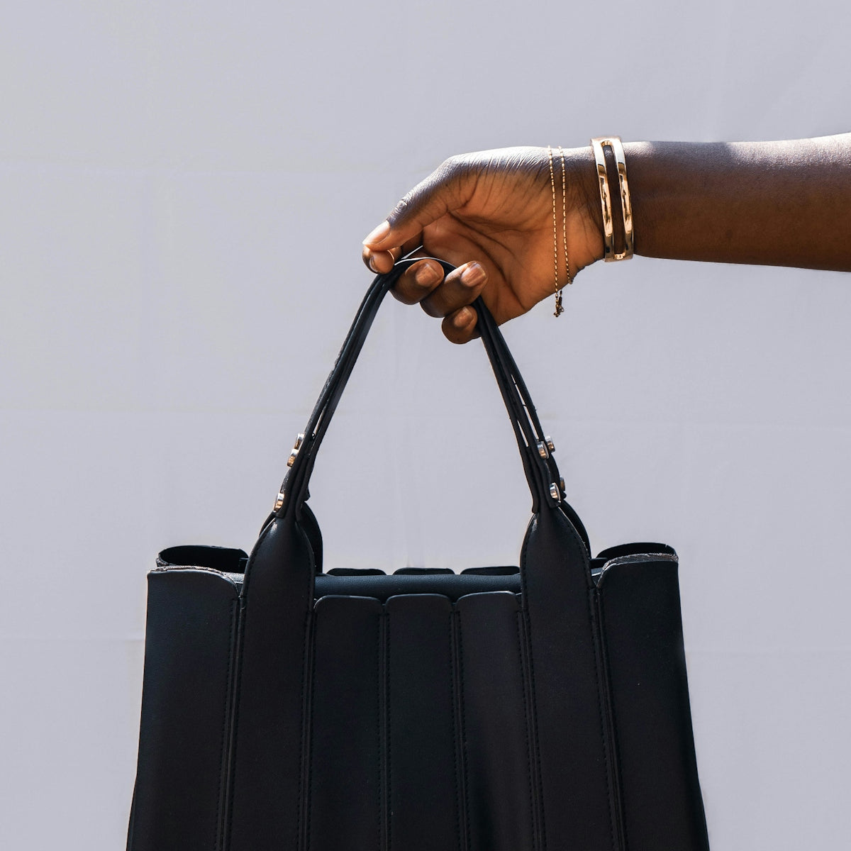 person holding black leather sling bag