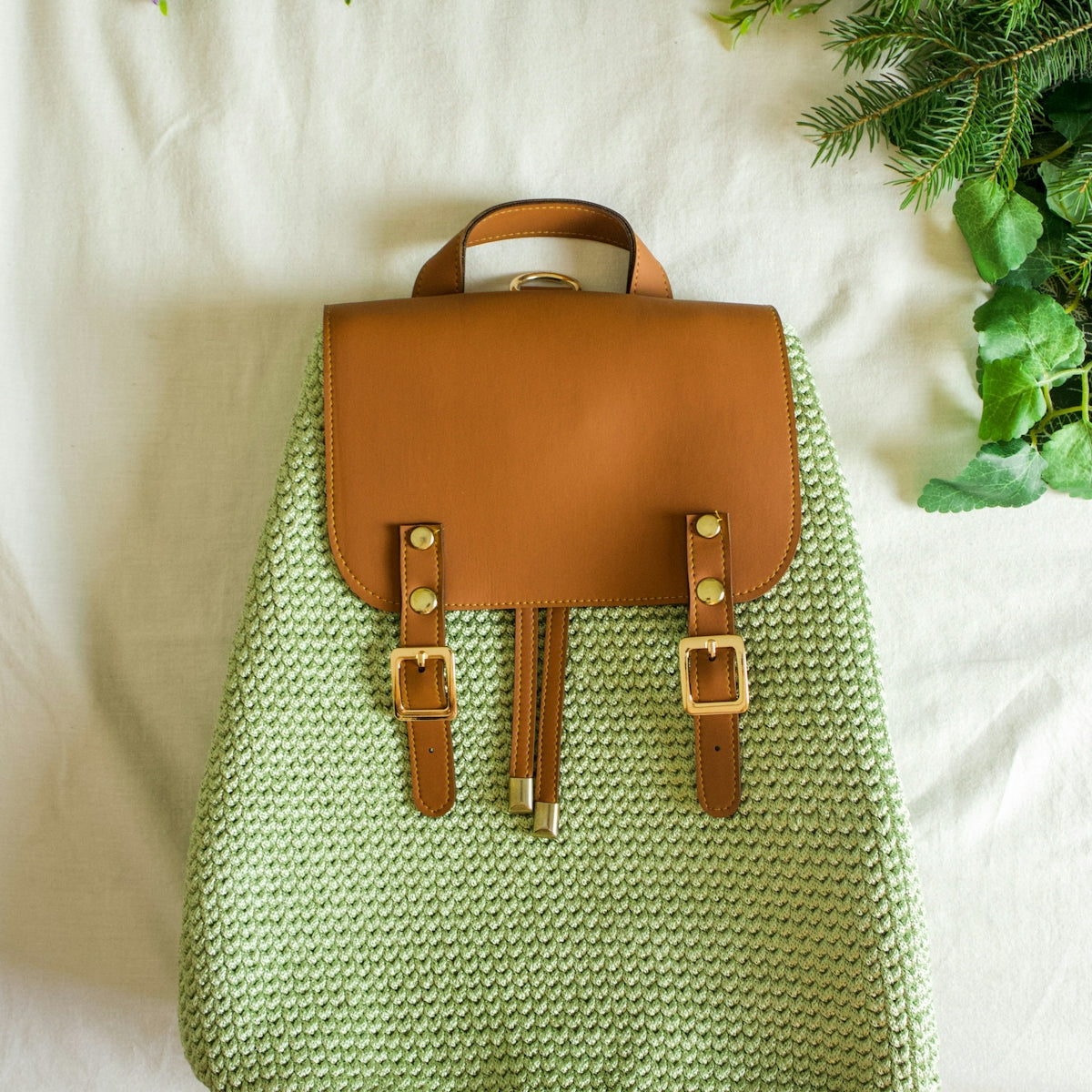 a handbag sitting on top of a bed next to a plant