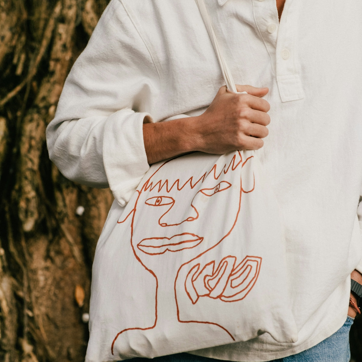 a man holding a bag with a drawing on it