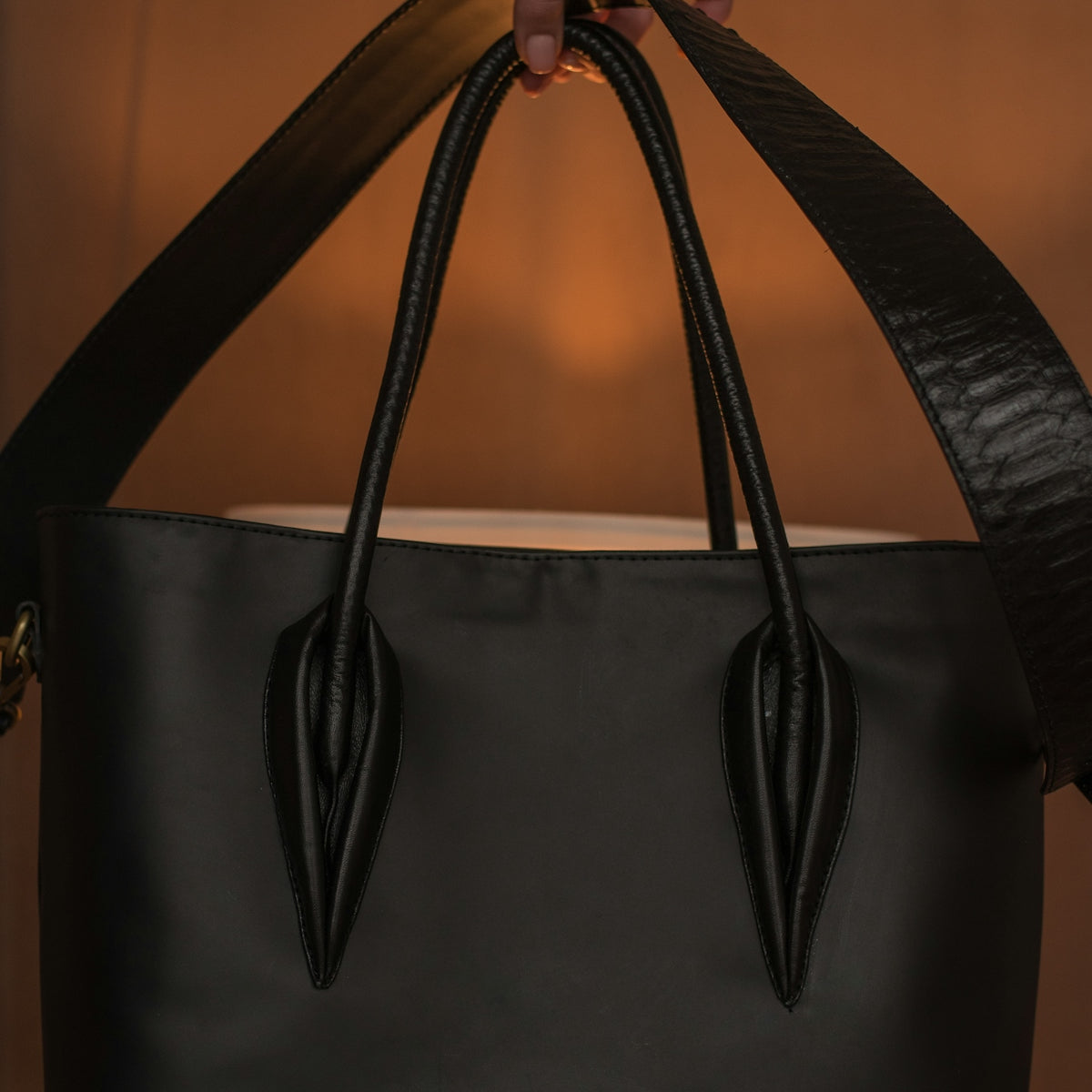 a person holding a black handbag in their left hand