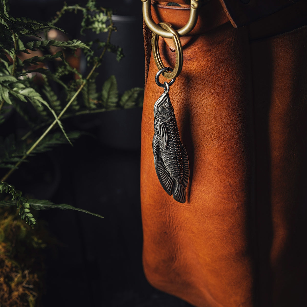 a brown leather bag with a feather charm hanging from it