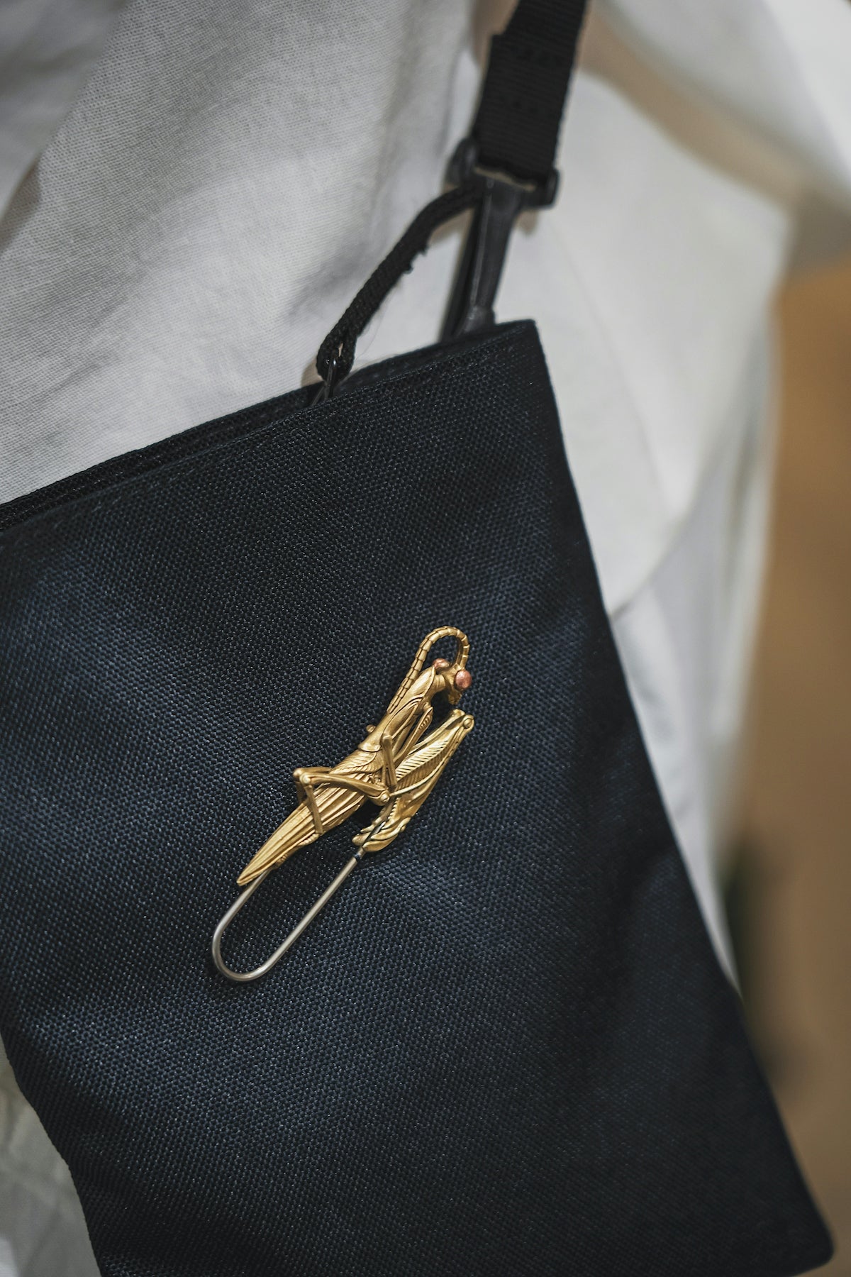 a person holding a black bag with a gold bird pin on it
