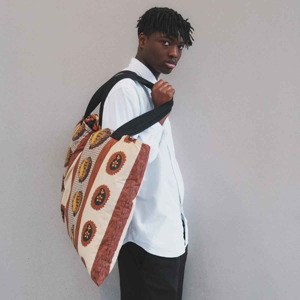 a man with a bag standing against a wall