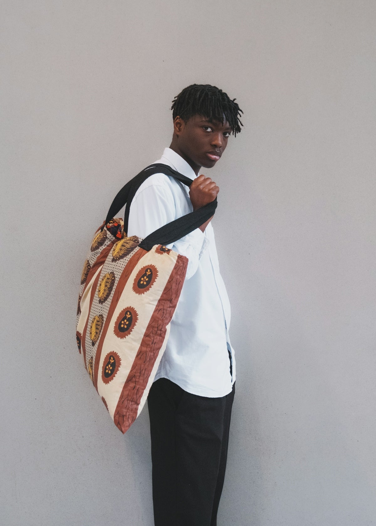 a man with a bag standing against a wall