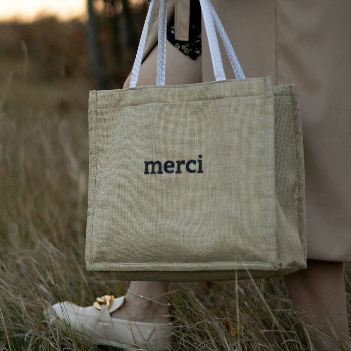 a person holding a bag with the word merci on it