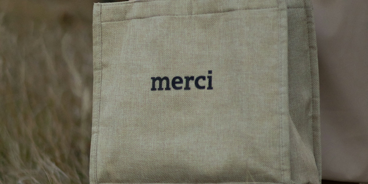 a person holding a bag with the word merci on it