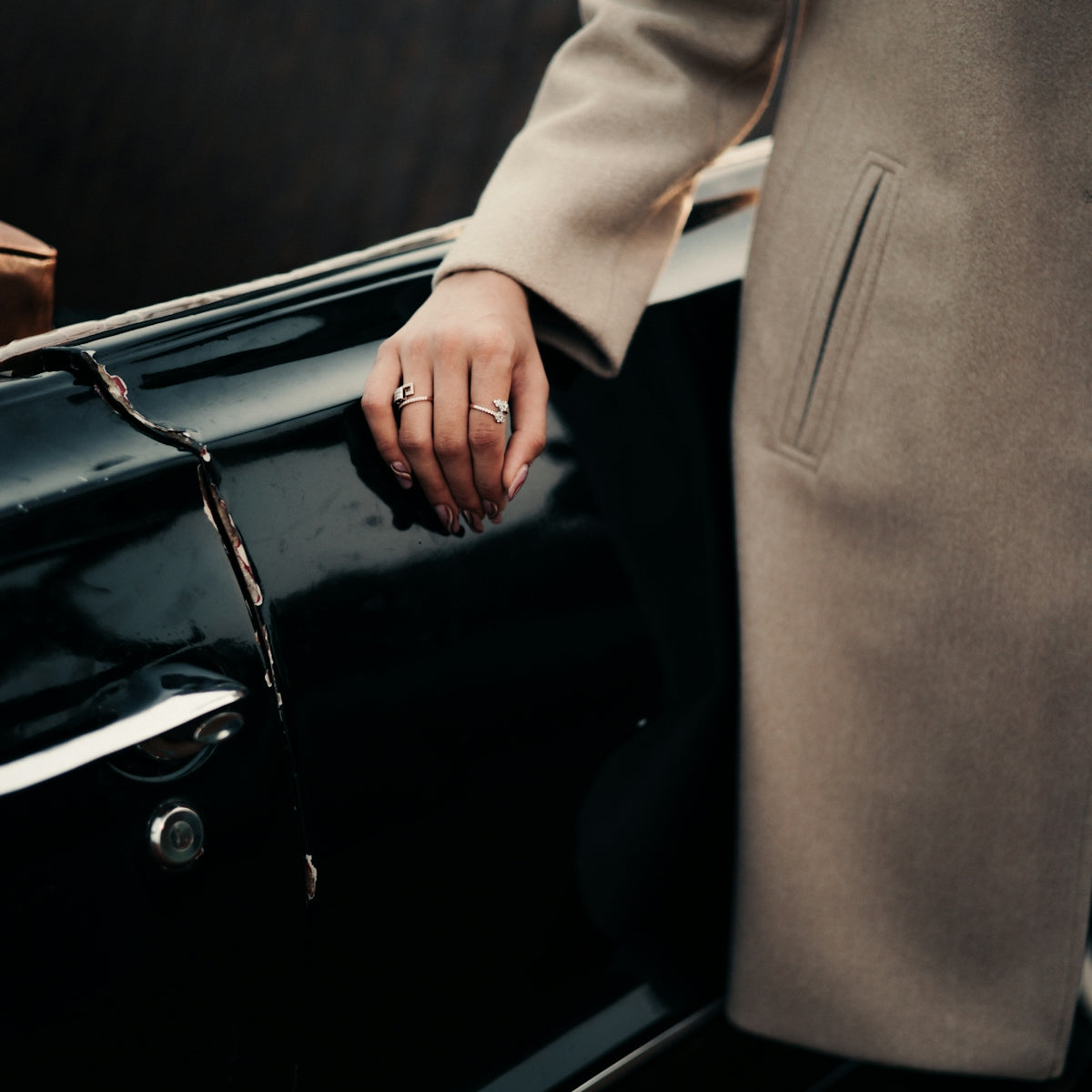 a person in a coat is holding onto a black car