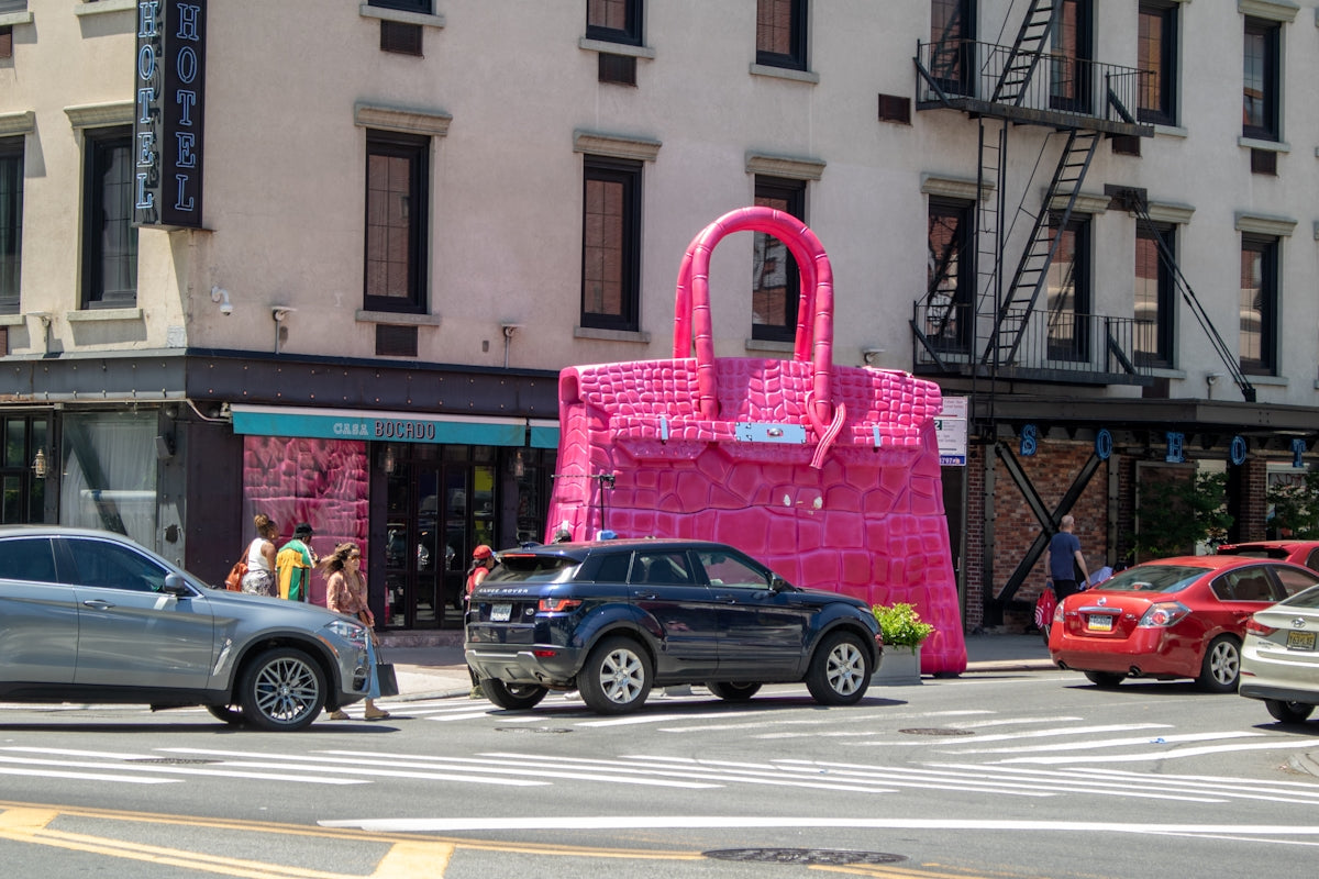 A large pink bag sitting on the side of a road