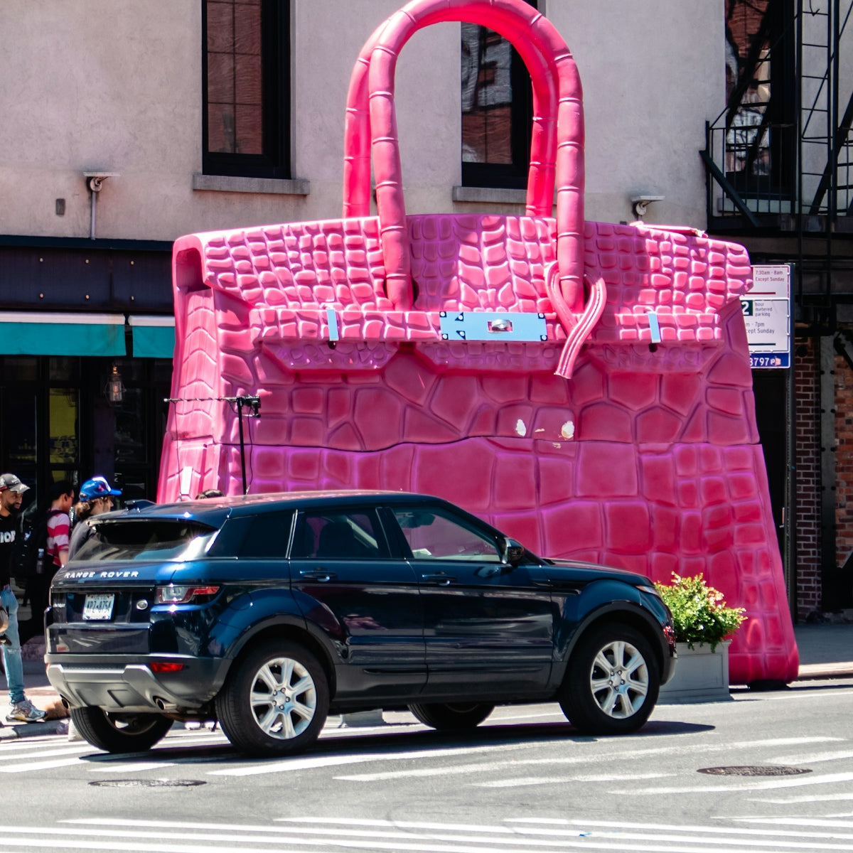 A car parked in front of a giant pink purse