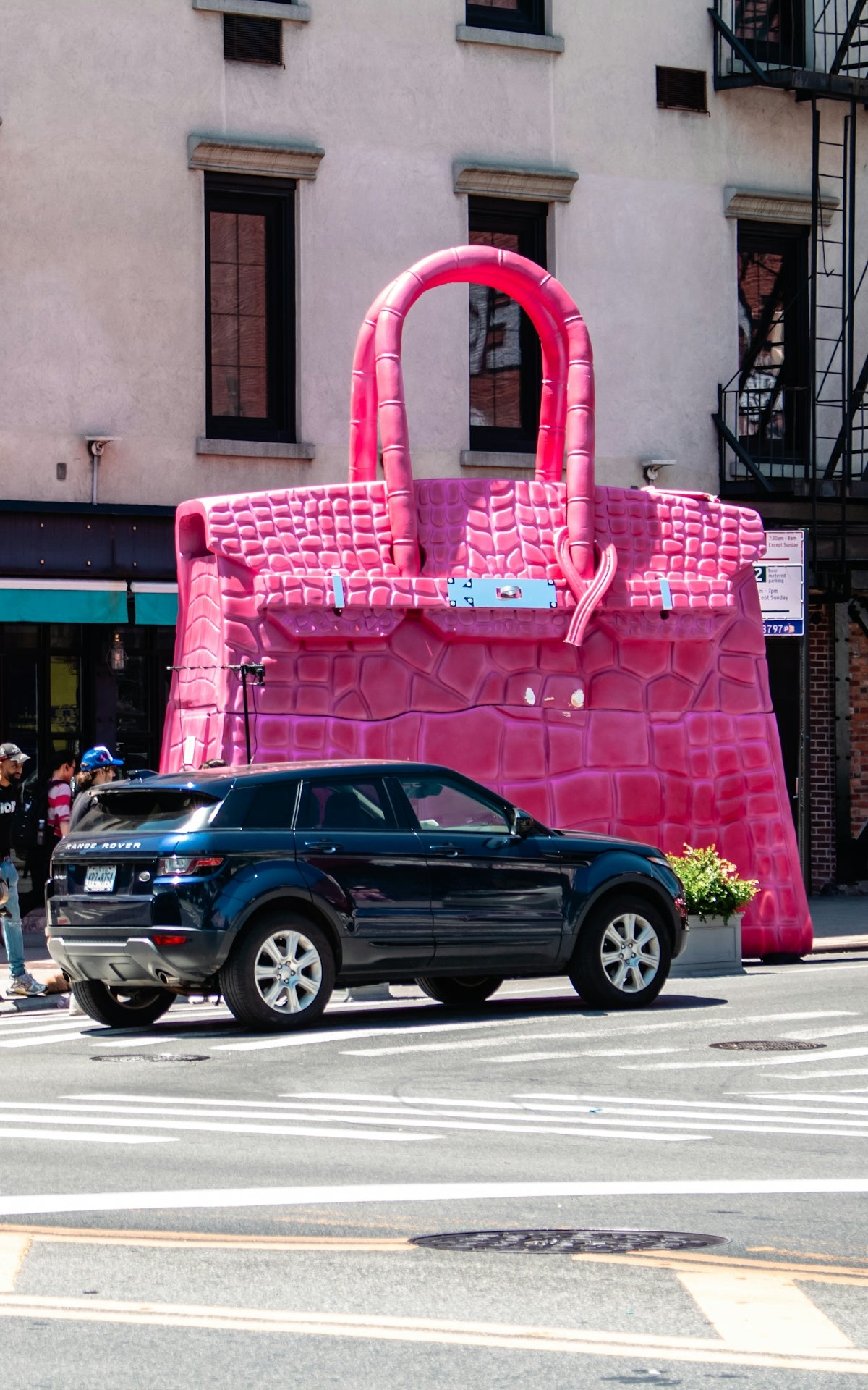 A car parked in front of a giant pink purse