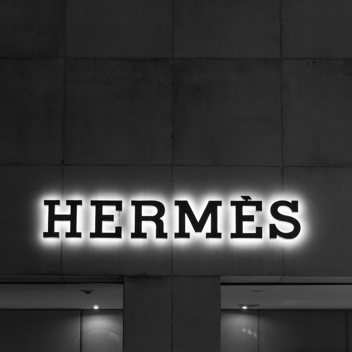 A black and white photo of a building with a neon sign