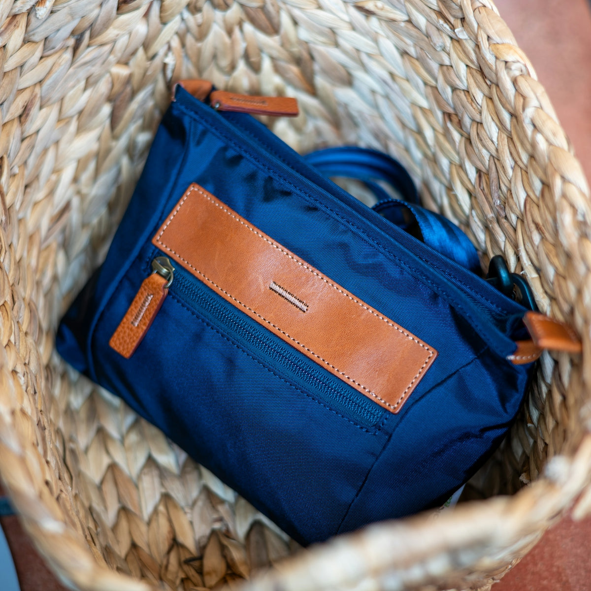 A blue bag rests in a wicker basket.