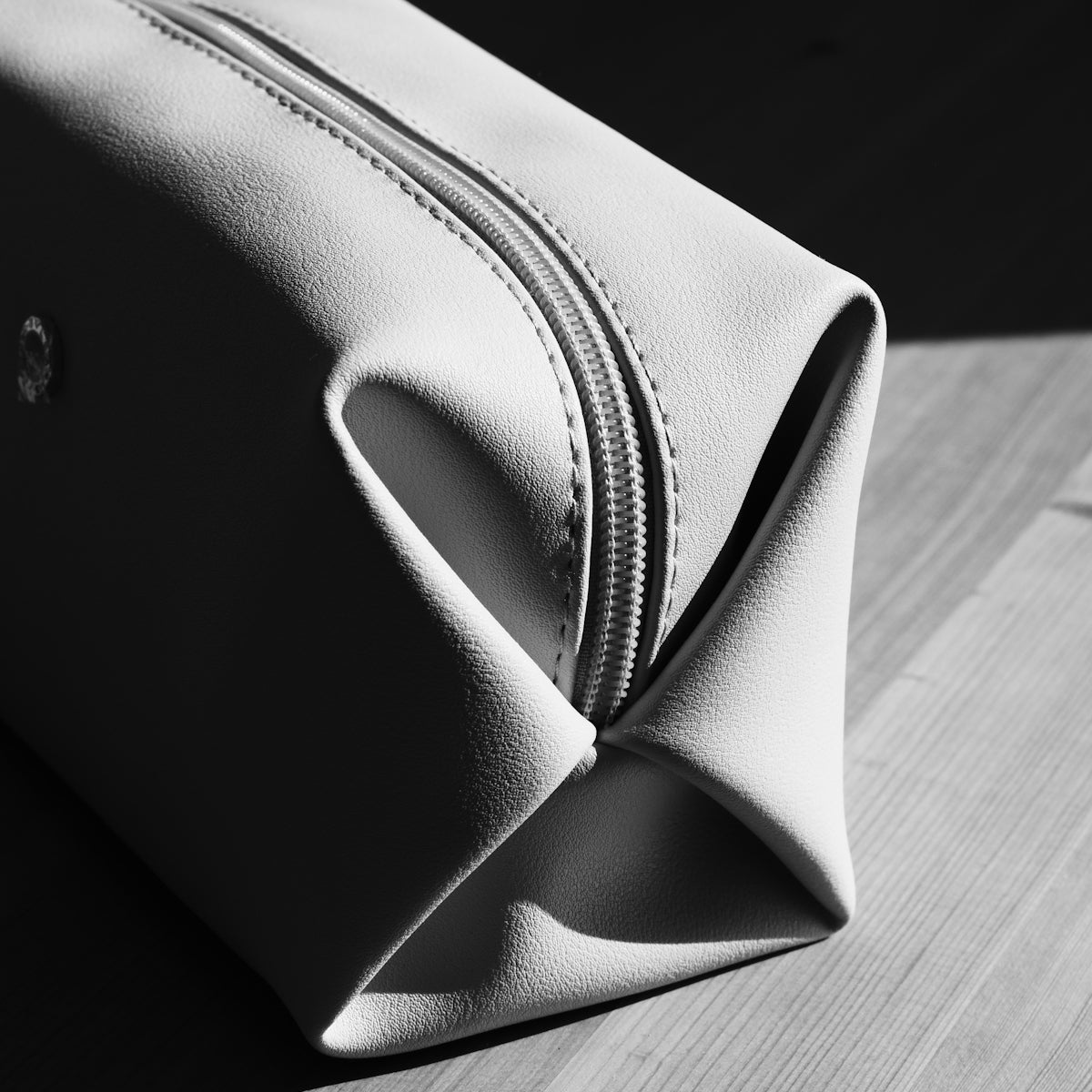 A light-colored toiletry bag on a wooden surface.
