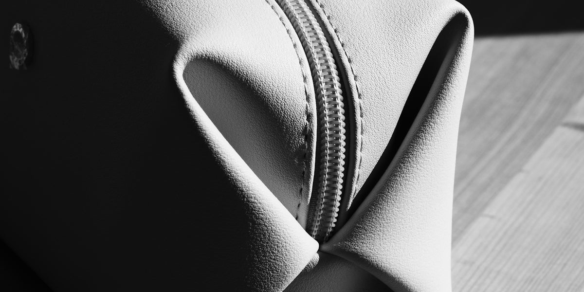 A light-colored toiletry bag on a wooden surface.