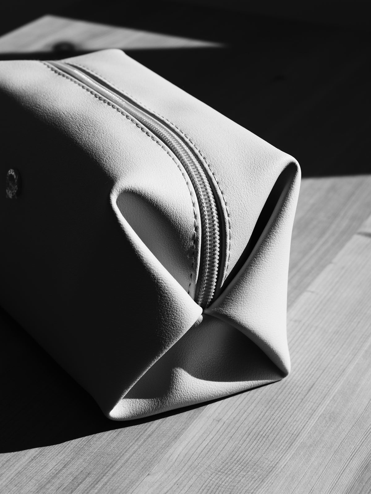 A light-colored toiletry bag on a wooden surface.