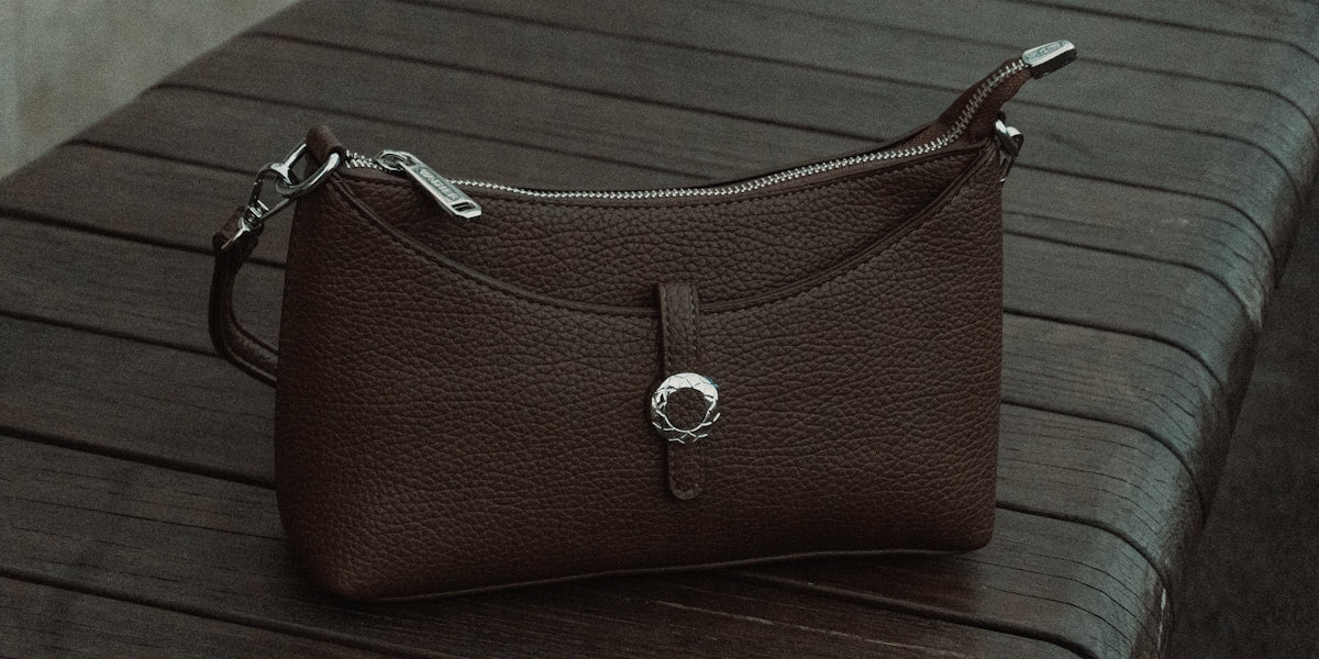 A brown leather handbag rests on a wooden surface.