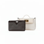 Black inner bag organizer with chevron stitching in front of a white luxury handbag
