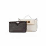 Black inner bag organizer with chevron stitching in front of a white luxury handbag